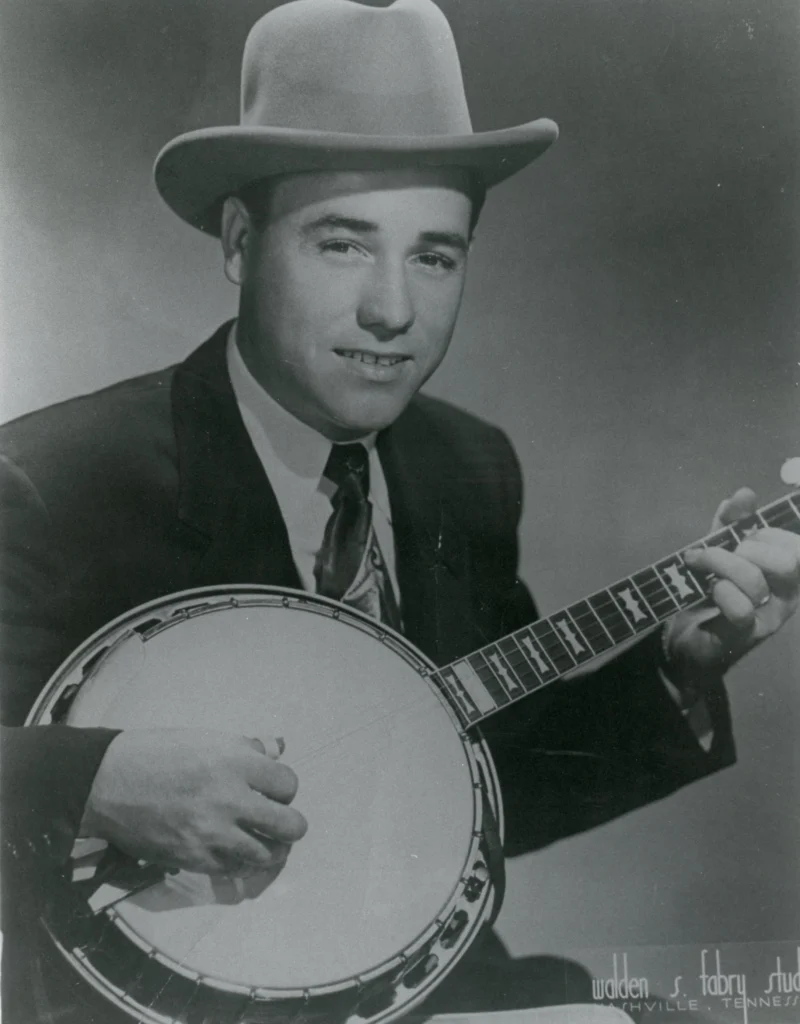 Earl Scruggs, a young white man, holds his banjo in this black and white photo.