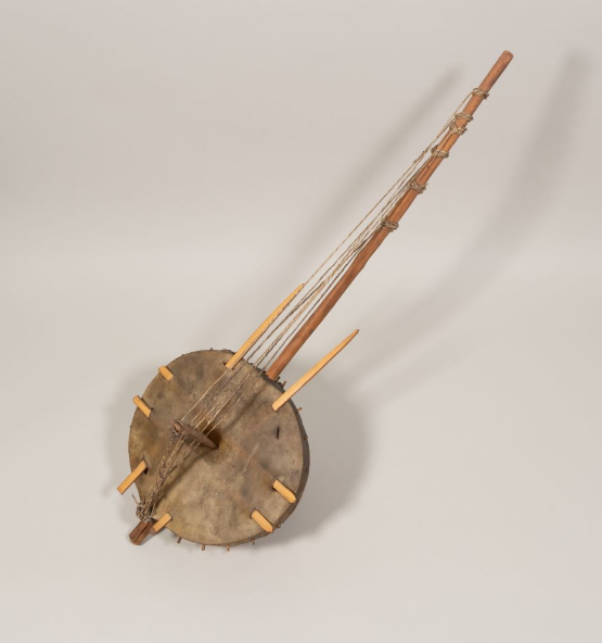 This lute has a round base connected to a long neck with strings. There are wooden sticks coming from the base.