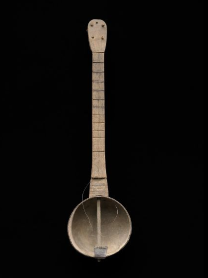 This banjo has a hollow, round gourd base with a fretted neck with tuning pegs.