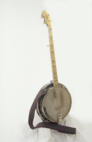 This banjo has a round base and fretted neck with at least five tuning pegs and five strings. It has a patterned should strap attached to the base.