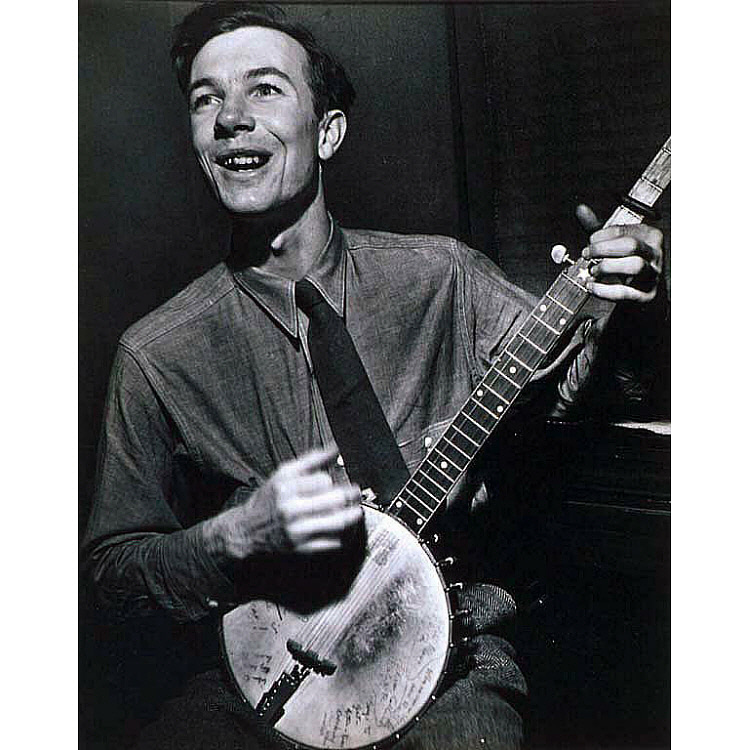 A black and white image of Pete Seeger, a young, white man in the middle of playing his banjo.