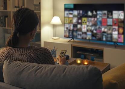 Woman on couch watching a streaming platform