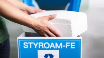 Photo of hands putting stryrofoam in a special recycling container.