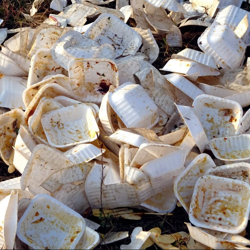 A pile of dirty styrofoam food containers on the ground